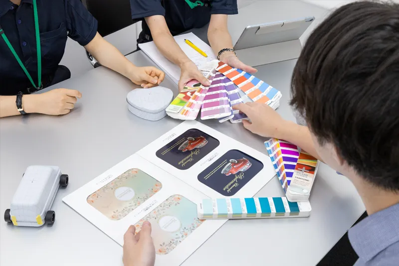 色のサンプルを見て打ち合わせする社員